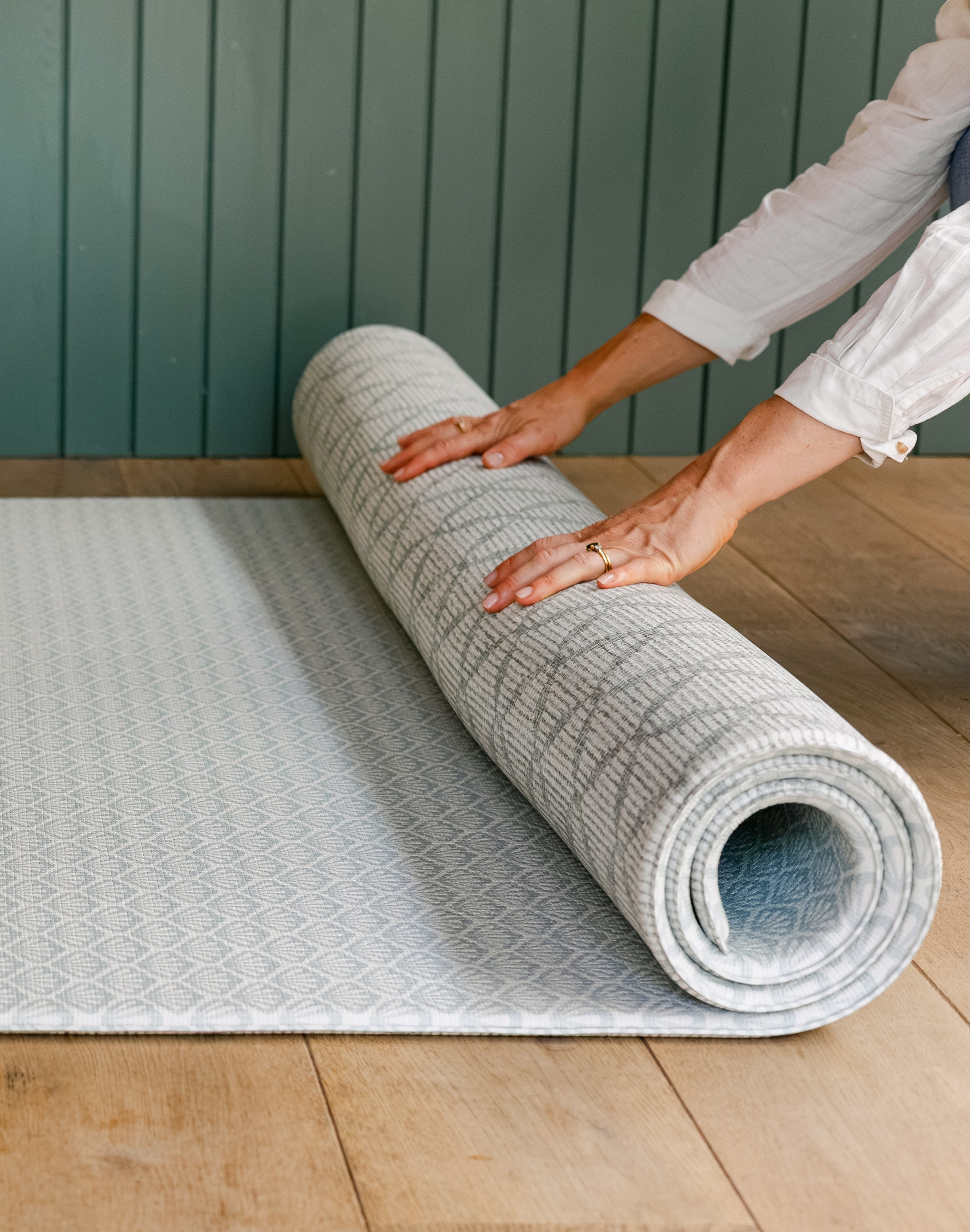 A person rolling the beachcomber coastal inspired hell design playmat from totter and tumble showing it's reversible design | SKU: 26 BEACH/GATHER XL, 26 BEACH/GATHER STD, 26 BEACH/GATHER COMP