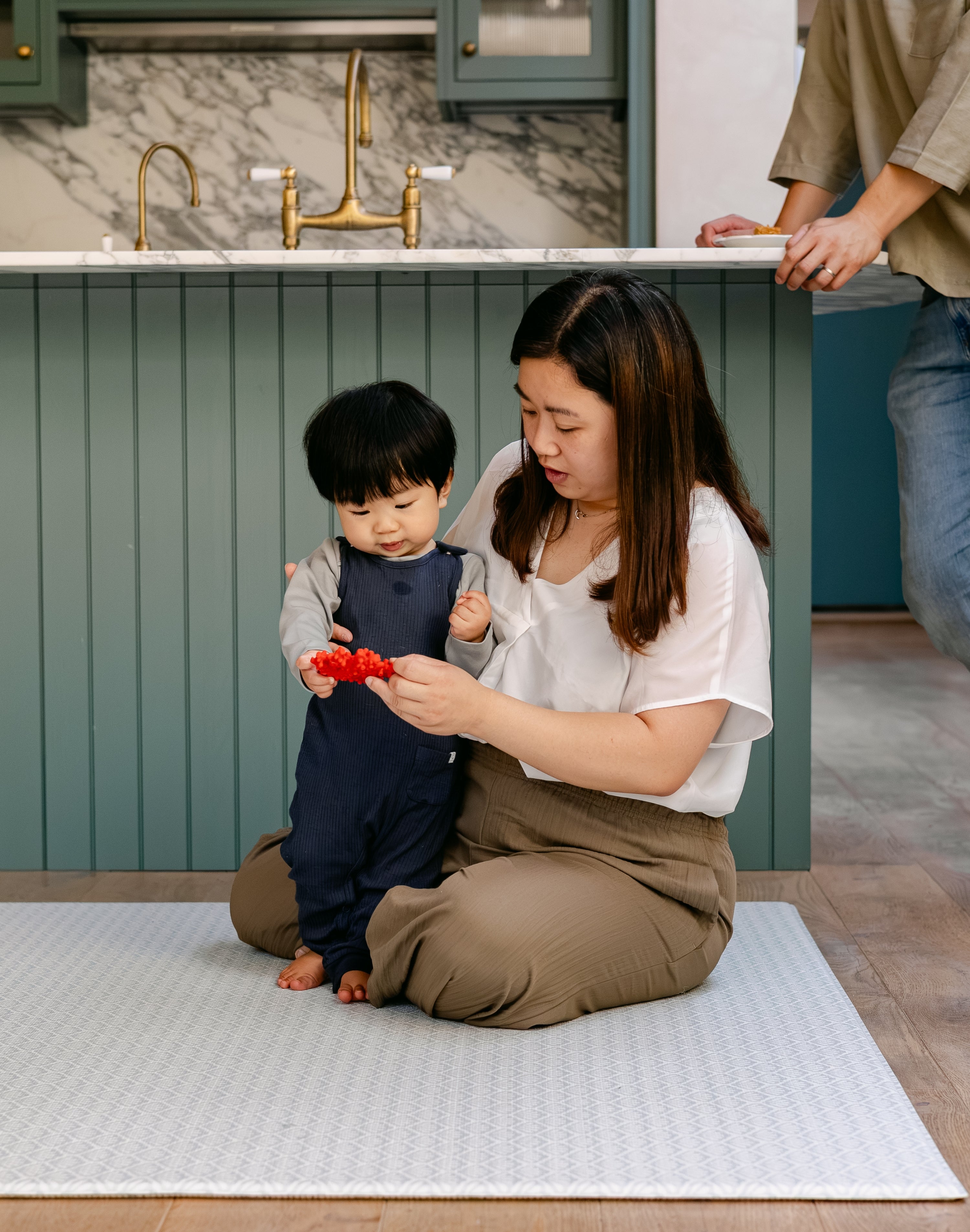 A family sat on the shell design, rug-like beachcomber playmat in a kitchen