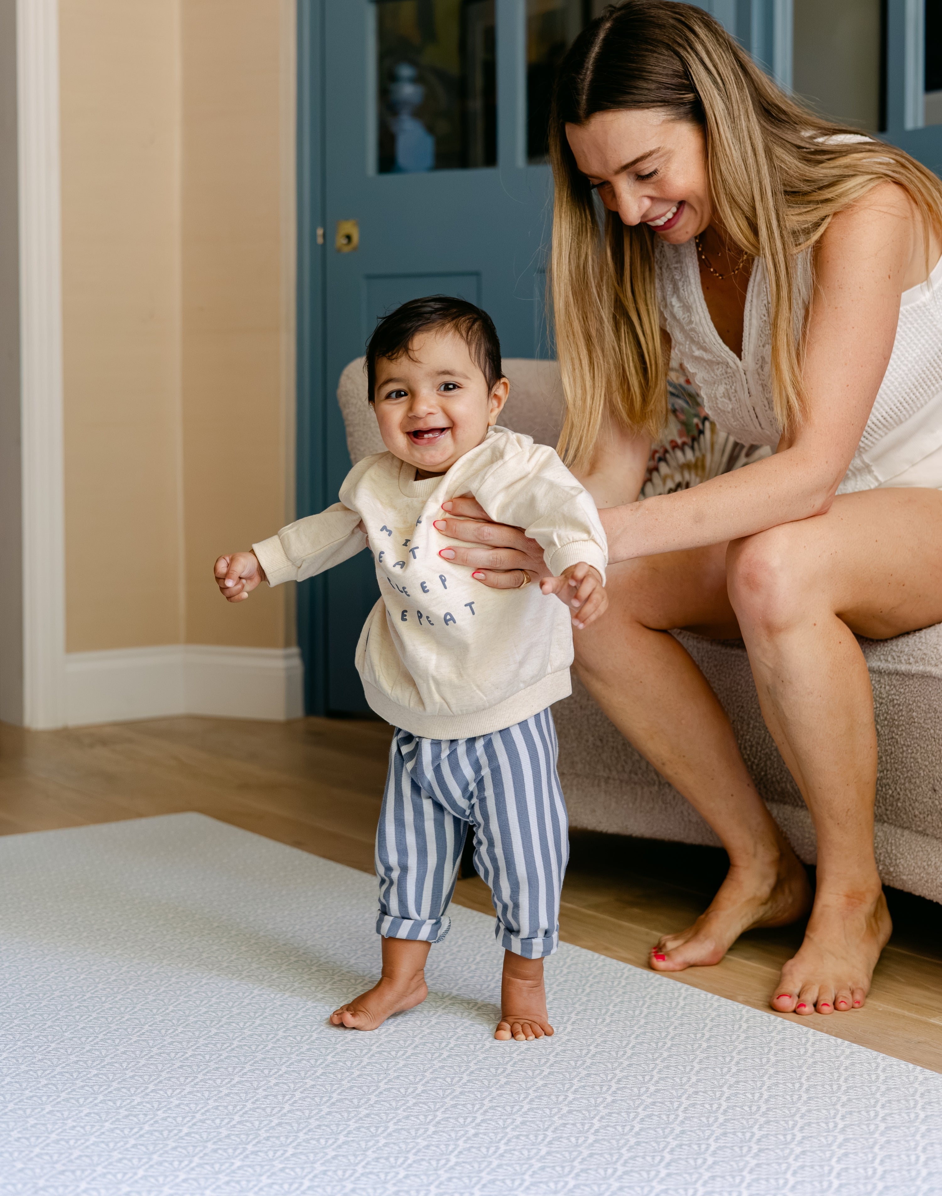 A woman helping her baby take some steps safely and comfortably on the beachcomber playmat | SKU: 26 BEACH/GATHER XL, 26 BEACH/GATHER STD, 26 BEACH/GATHER COMP