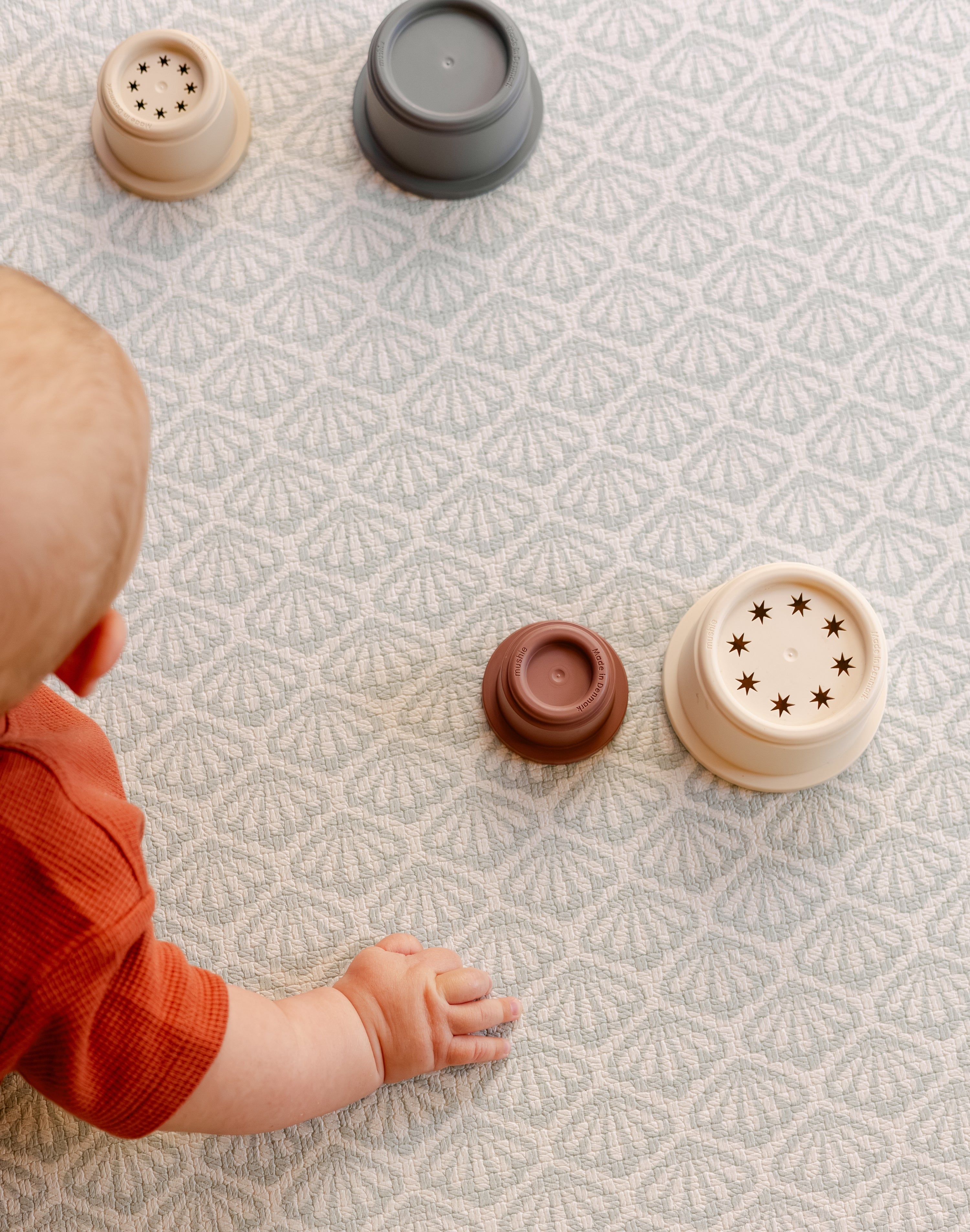 A baby reaching for some toys on a safe non toxic beachcomber playmat suitable from birth | SKU: 26 BEACH/GATHER XL, 26 BEACH/GATHER STD, 26 BEACH/GATHER COMP
