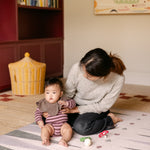 Mum and baby sitting on The Counter wipeable reversible memory foam playmat from Totter + Tumble