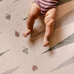 Baby lying on The Counter wipeable reversible memory foam playmat from Totter + Tumble