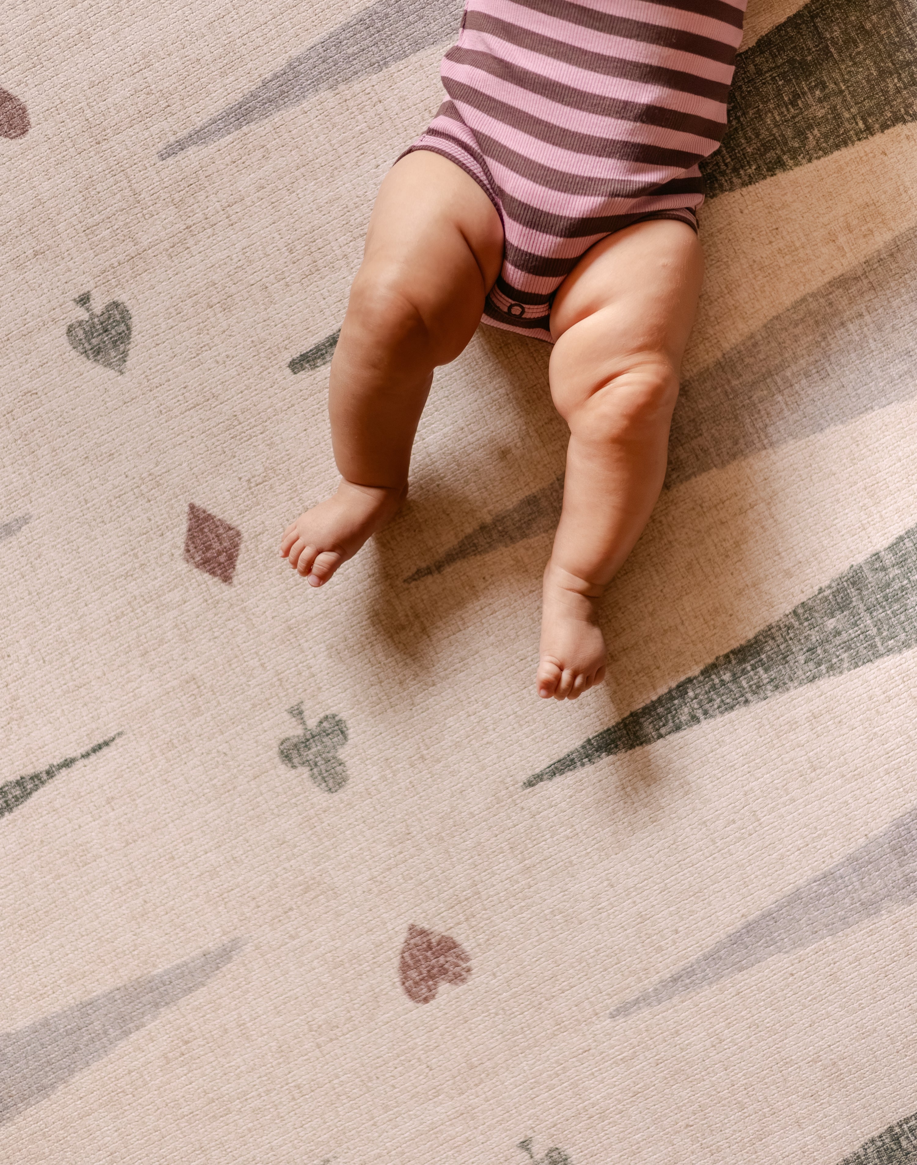 Baby lying on The Counter wipeable reversible memory foam playmat from Totter + Tumble
