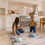 Mum and toddler on balance blocks on The Counter wipeable reversible memory foam playmat from Totter + Tumble in a bright kitchen