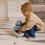 Child stacking on The Counter wipeable reversible memory foam playmat from Totter + Tumble