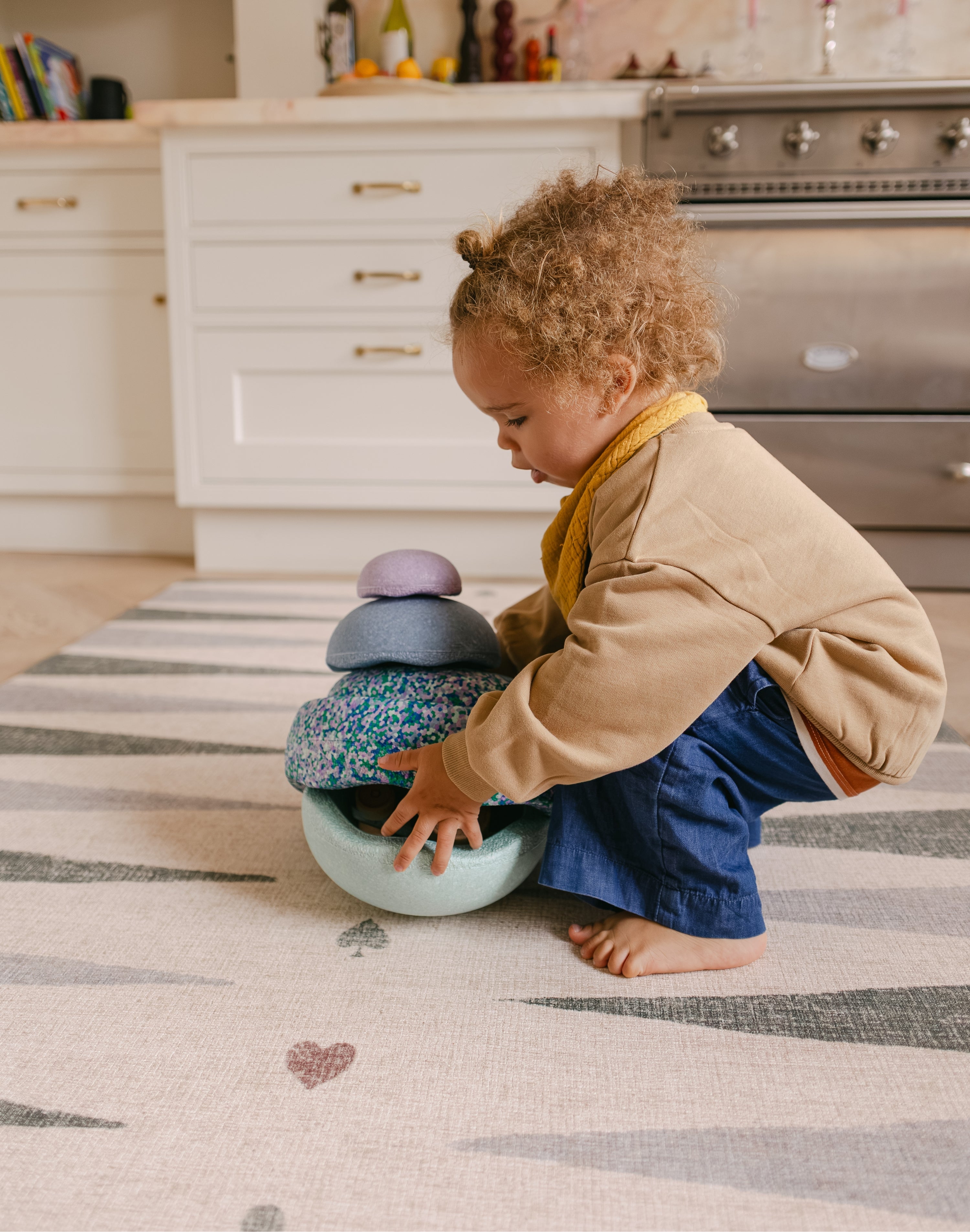 Child stacking on The Counter wipeable reversible memory foam playmat from Totter + Tumble