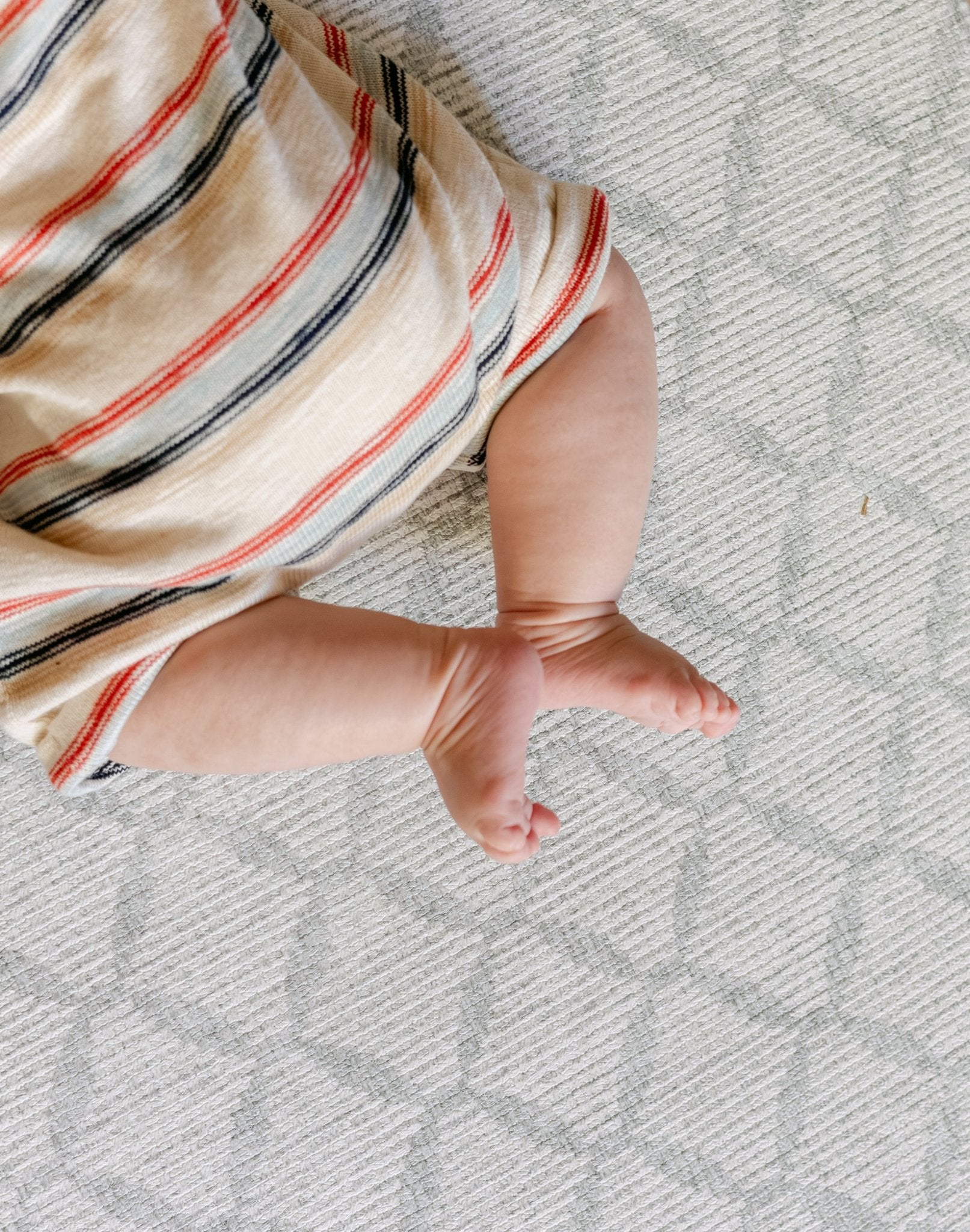 A close up on a baby's feet on the gatherer coastal inspired playmat design | SKU: 26 BEACH/GATHER XL, 26 BEACH/GATHER STD, 26 BEACH/GATHER COMP