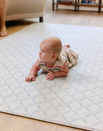 A baby laying on the gatherer playmat from totter and tumble, soft, safe and made from thick memory foam