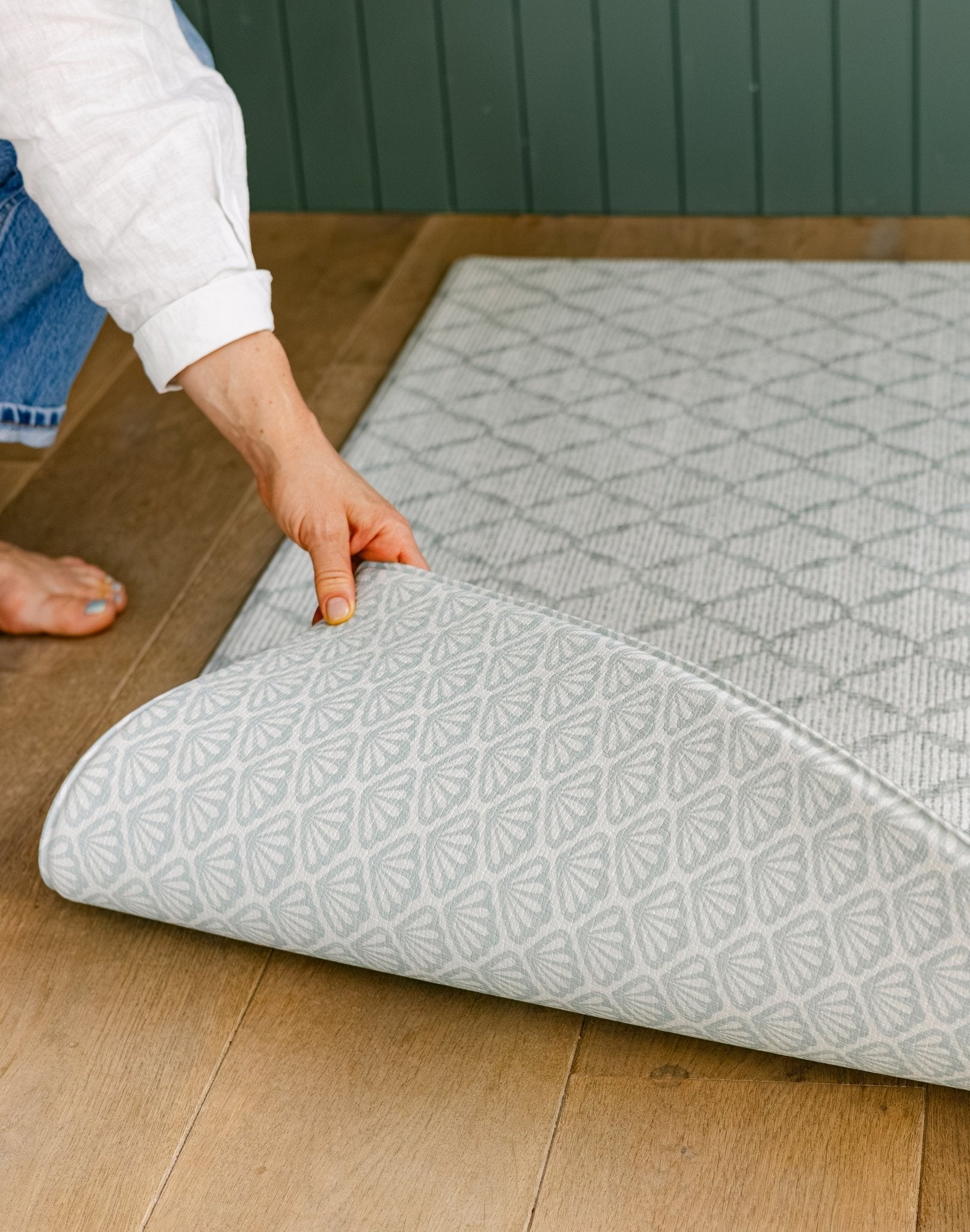 A person showing two sides on a reversible shell and coastal inspired design totter and tumble playmat | SKU: 26 BEACH/GATHER XL, 26 BEACH/GATHER STD, 26 BEACH/GATHER COMP