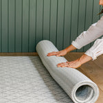 A woman rolling up the reversible gatherer and beachcomber playmat from totter and tumble | SKU: 26 BEACH/GATHER XL, 26 BEACH/GATHER STD, 26 BEACH/GATHER COMP