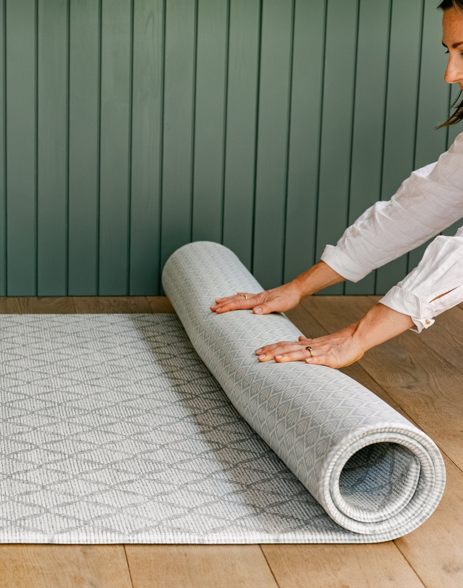 A woman rolling up the reversible gatherer and beachcomber playmat from totter and tumble | SKU: 26 BEACH/GATHER XL, 26 BEACH/GATHER STD, 26 BEACH/GATHER COMP