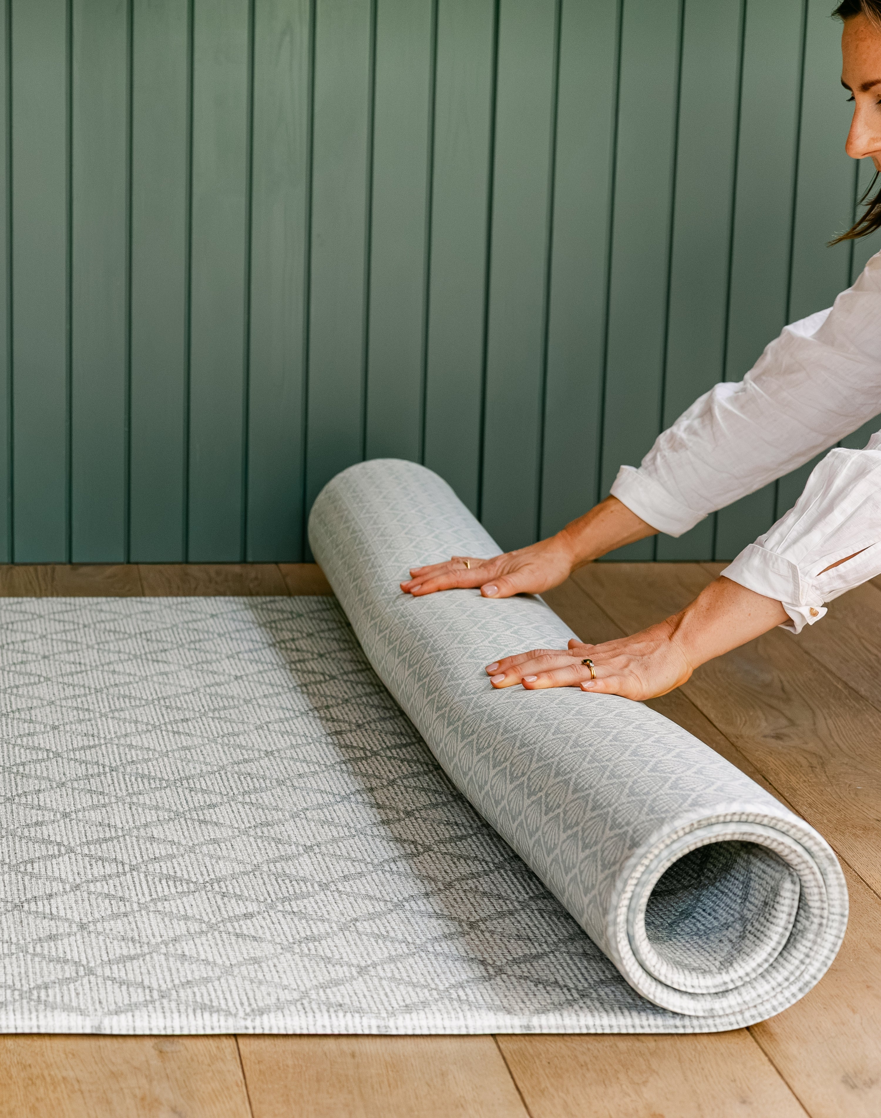 A woman rolling up the reversible gatherer and beachcomber playmat from totter and tumble | SKU: 26 BEACH/GATHER XL, 26 BEACH/GATHER STD, 26 BEACH/GATHER COMP