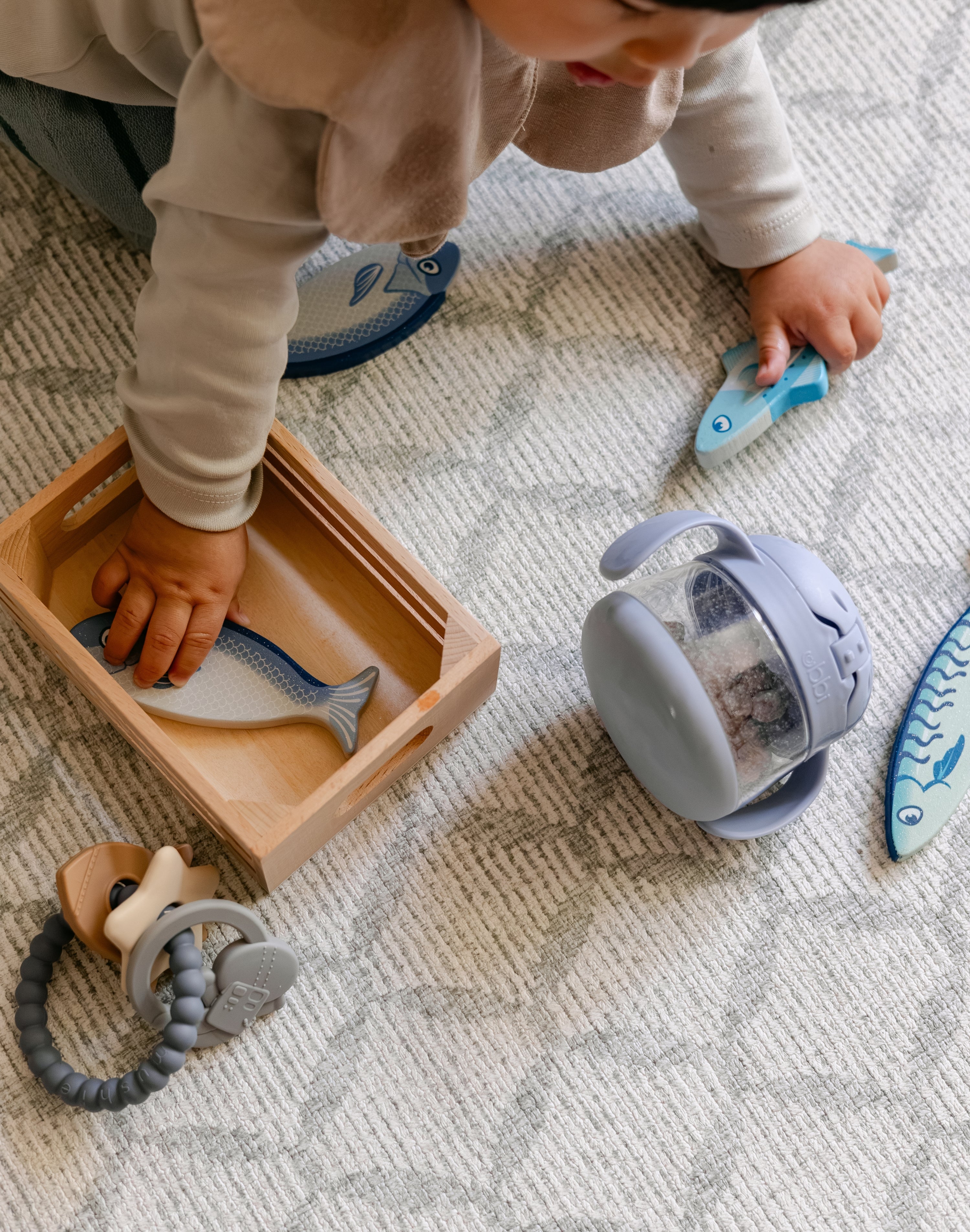 A baby playing with toys on a rug-like, supportive, totter and tumble memory foam playmat | SKU: 26 BEACH/GATHER XL, 26 BEACH/GATHER STD, 26 BEACH/GATHER COMP