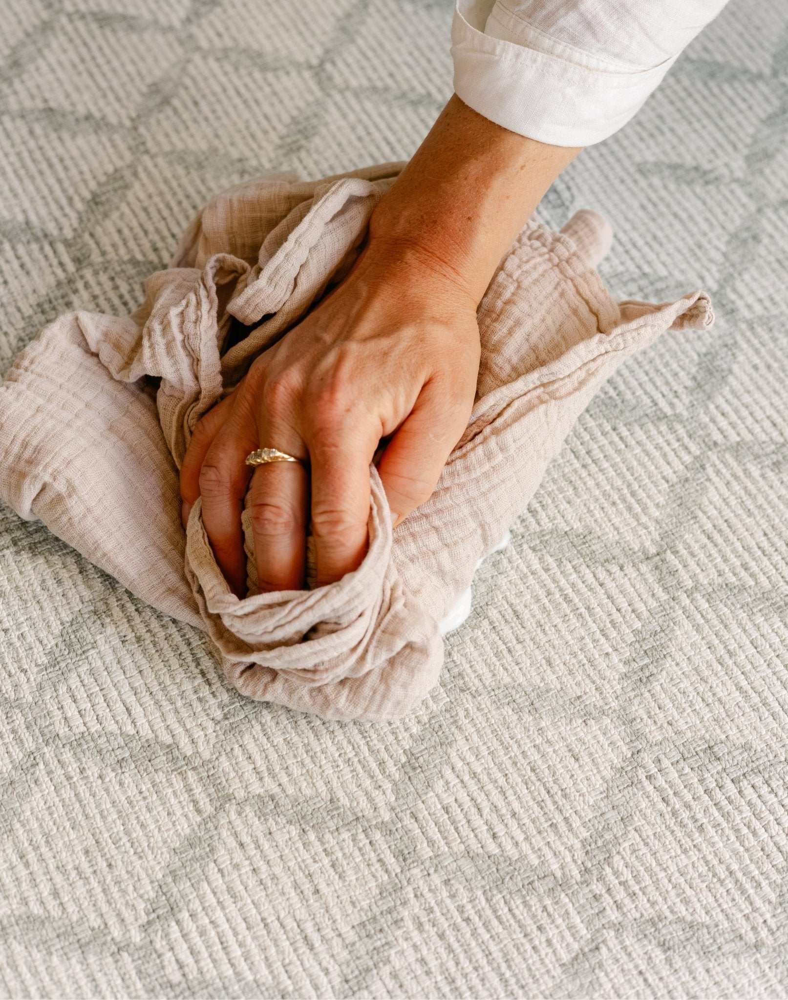 A close-up of a person's hand  easily wiping down the gatherer playmat from totter and tumble | SKU: 26 BEACH/GATHER XL, 26 BEACH/GATHER STD, 26 BEACH/GATHER COMP