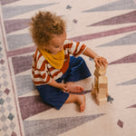 Child stacking blocks on The Roller XL reversible memory foam playmat by Totter + Tumble, the largest one piece playmat on the market