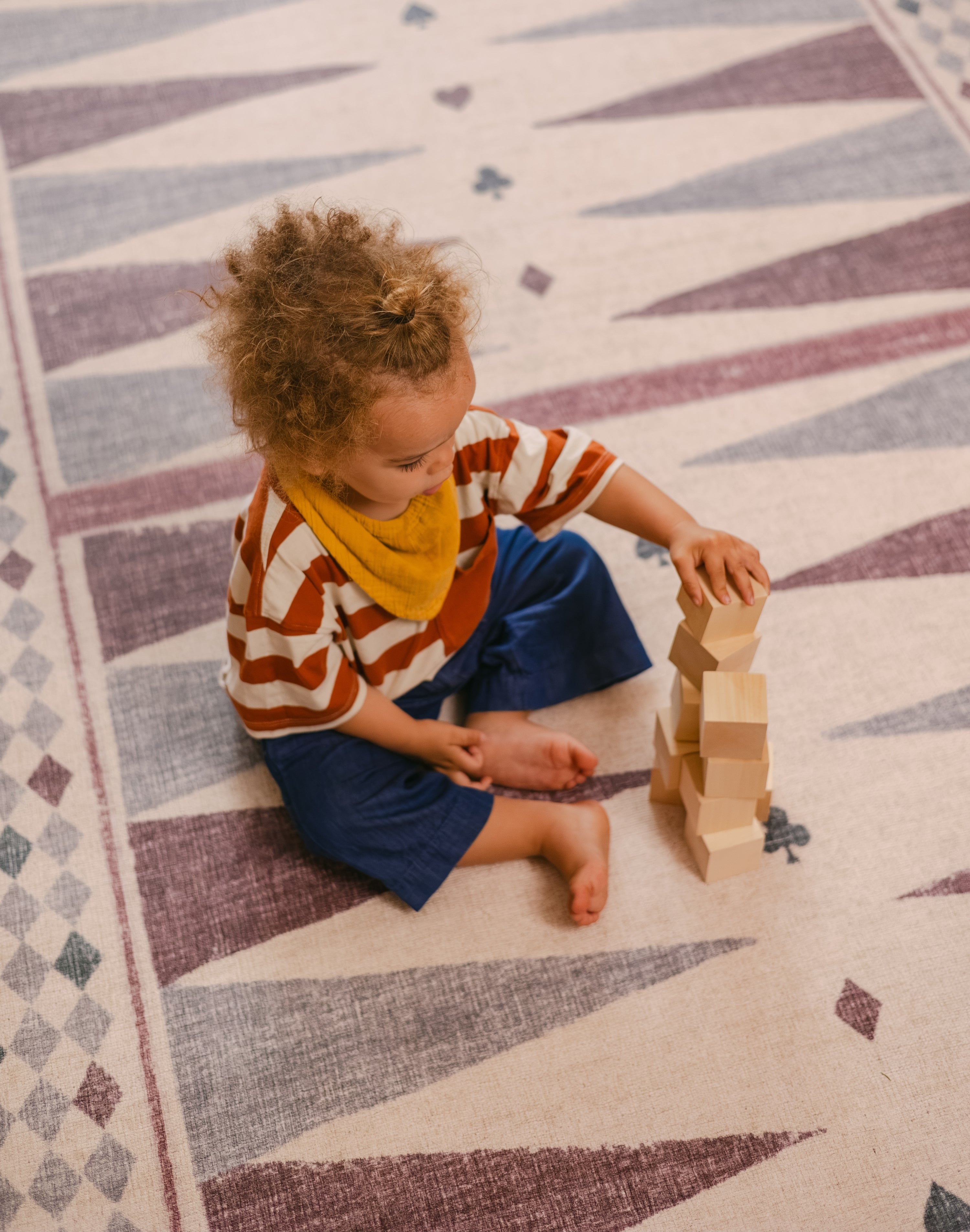 Child stacking blocks on The Roller XL reversible memory foam playmat by Totter + Tumble, the largest one piece playmat on the market