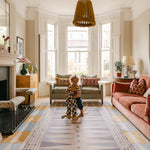 Child on rocking horse in bright living room on The Roller XL reversible memory foam playmat by Totter + Tumble, the largest one piece playmat on the market