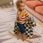 Child on a rocking horse on The Roller XL reversible memory foam playmat by Totter + Tumble, the largest one piece playmat on the market