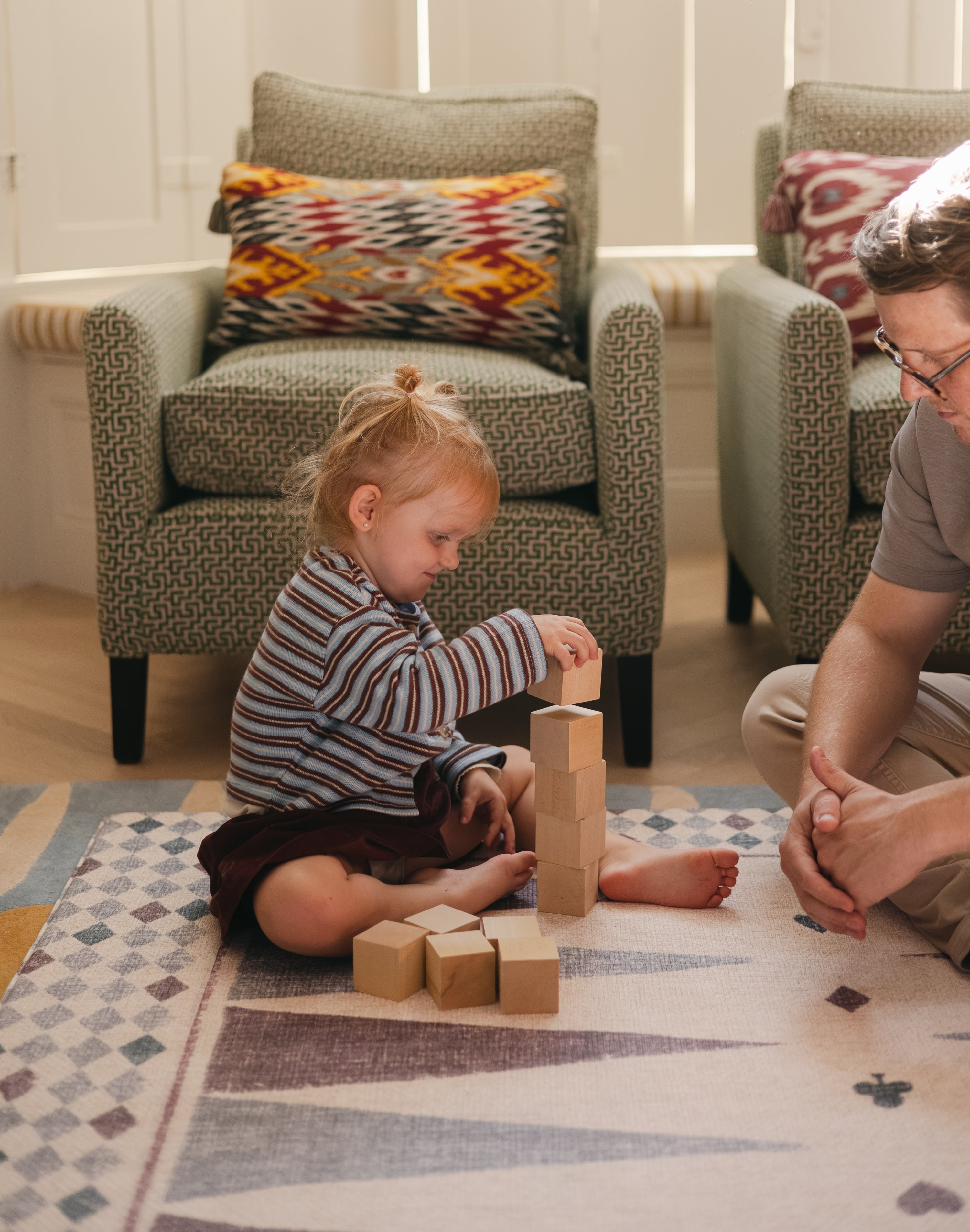 Todder and dad stacking blocks on The Roller XL reversible memory foam playmat by Totter + Tumble, the largest one piece playmat on the market