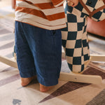 Child standing next to rocking horse on The Roller XL reversible memory foam playmat by Totter + Tumble, the largest one piece playmat on the market