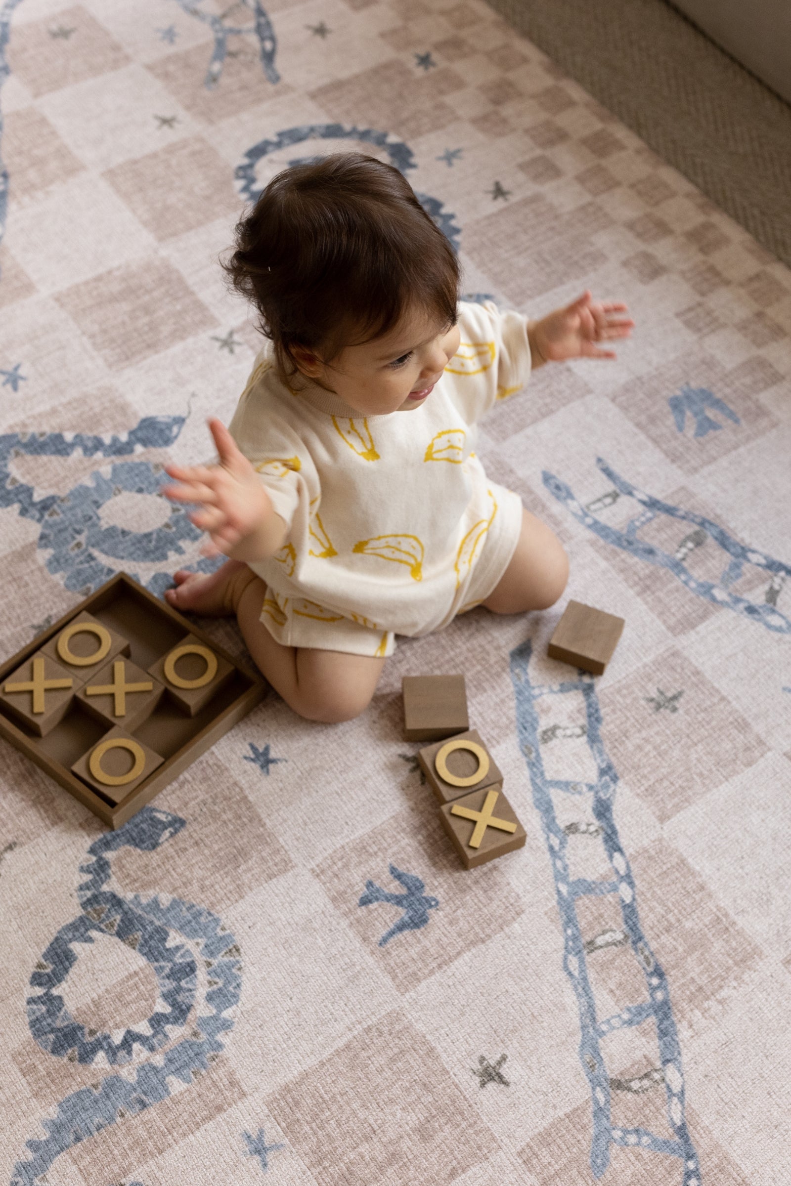 Child playing with wooden blocks on a retro Totter + Tumble play mat 