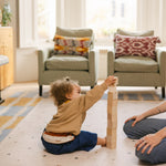 Toddler stacking bricks on The Wildcard reversible memory foam playmat by Totter + Tumble