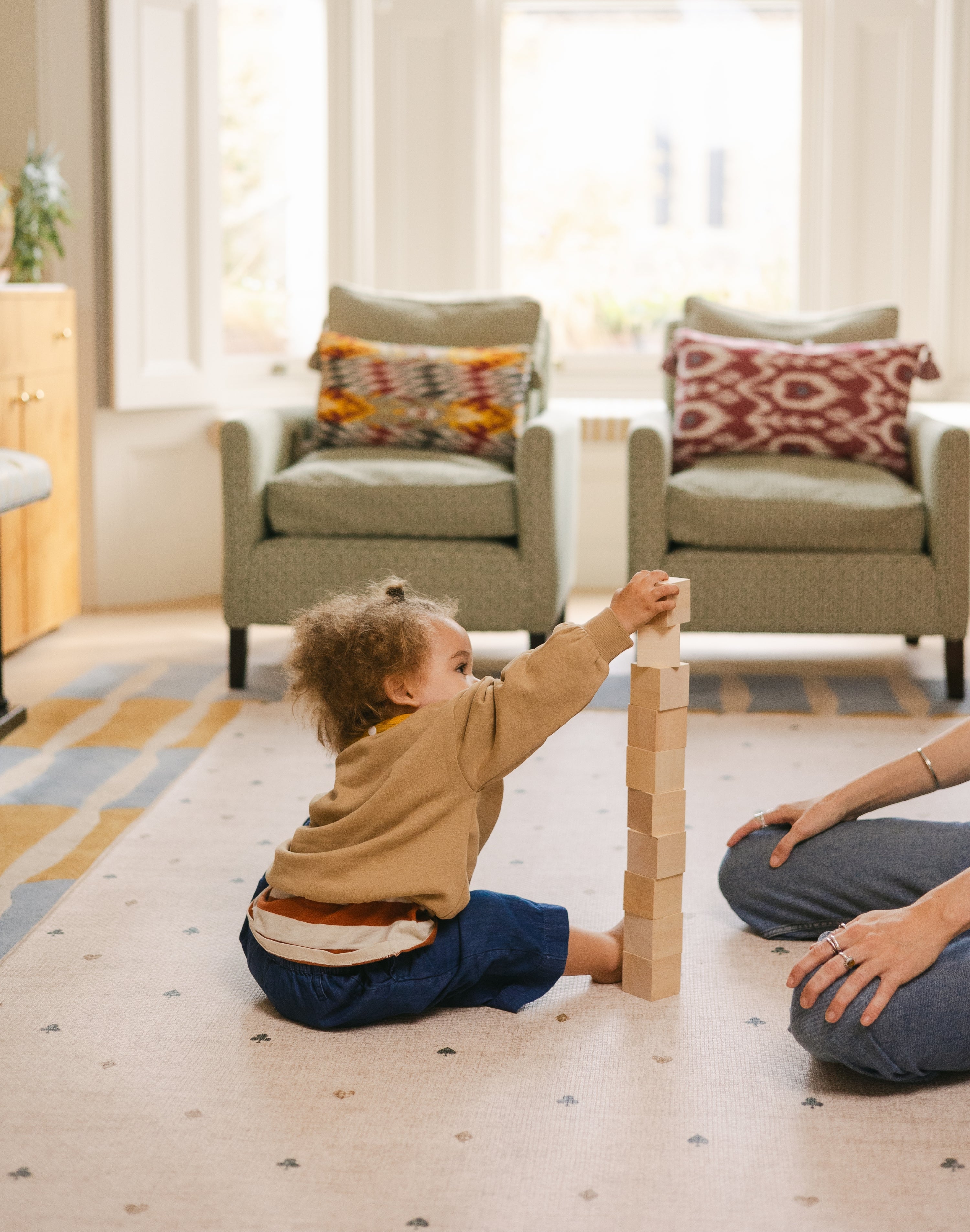 Toddler stacking bricks on The Wildcard reversible memory foam playmat by Totter + Tumble