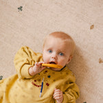 Baby lying on The Wildcard Totter + Tumble reversible memory foam playmat