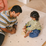 Child and man playing on The Wildcard Totter + Tumble reversible memory foam playmat