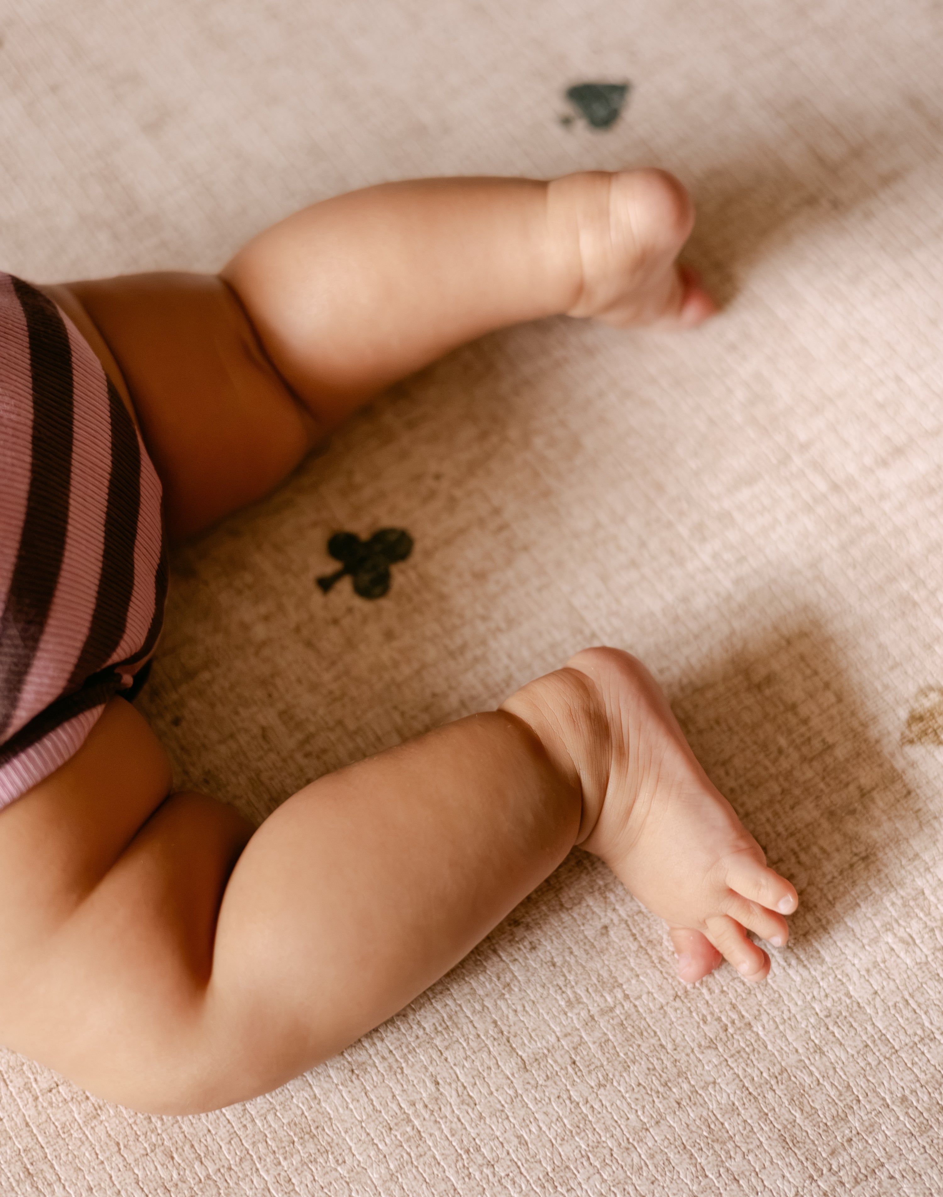 Baby legs on The Wildcard XL reversible memory foam playmat by Totter + Tumble, the largest one piece playmat on the market