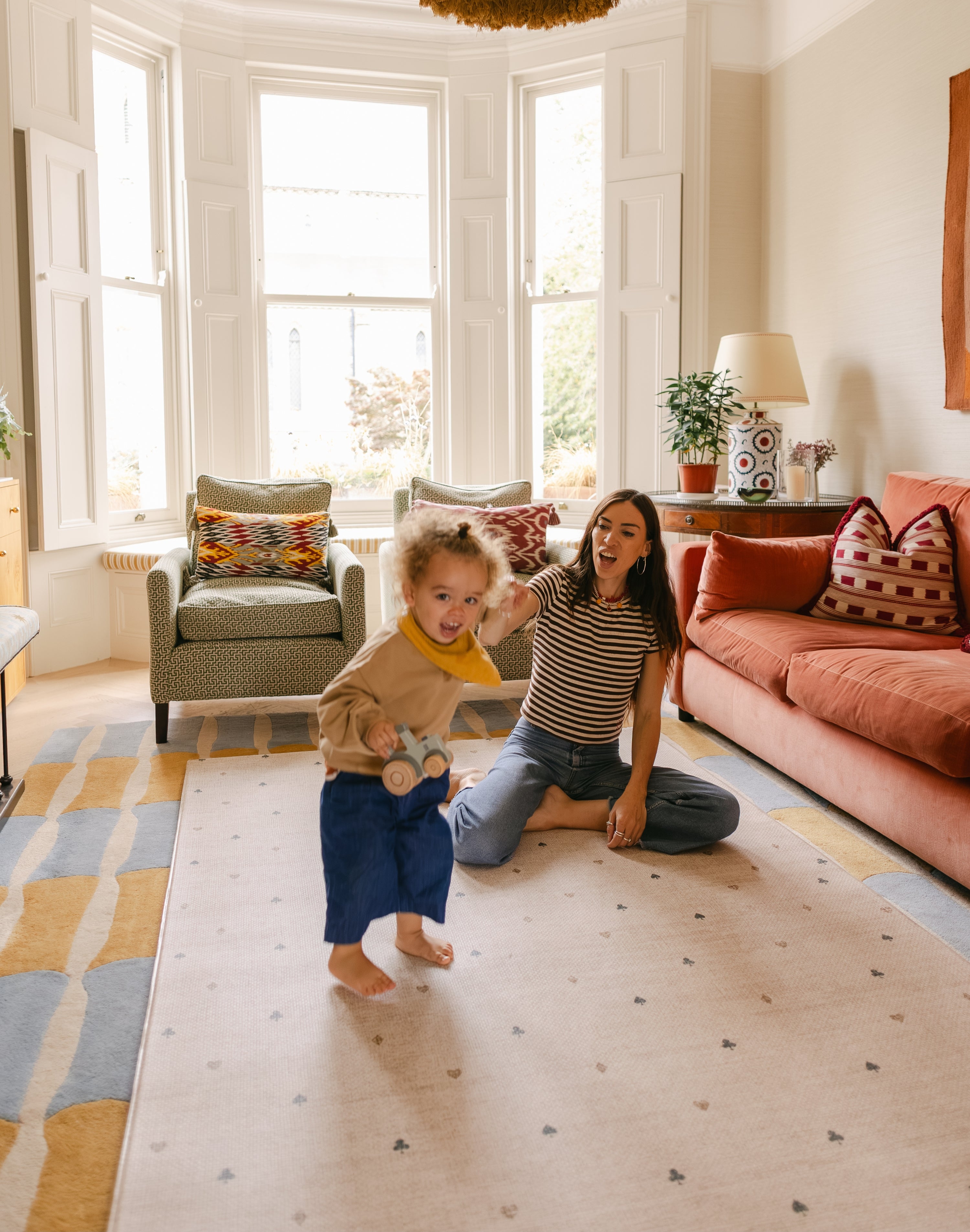 Toddler and mum playing on The Wildcard Totter + Tumble reversible memory foam playmat in bright colourful living space