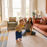 Mum and toddler playing on The Wildcard XL reversible memory foam playmat by Totter + Tumble, the largest one piece playmat on the market, in a bright colourful living space