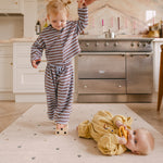 Toddler balancing on blocks on The Wildcard XL reversible memory foam playmat by Totter + Tumble, the largest one piece playmat on the market, and baby lying down