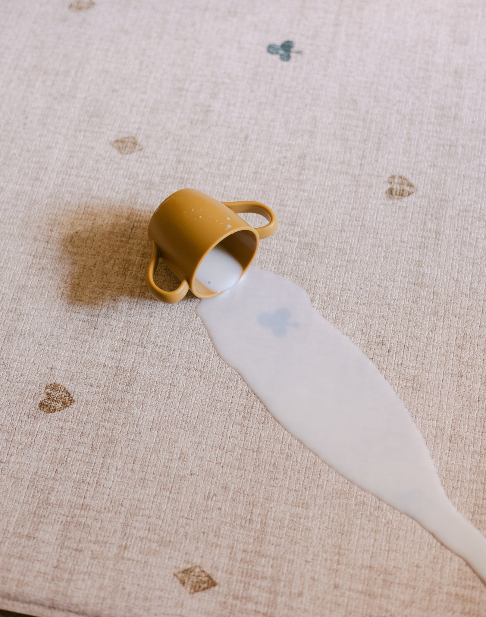 The Wildcard Totter + Tumble reversible memory foam playmat with milk spilled from a cup